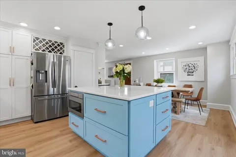 a kitchen with stainless steel appliances kitchen island granite countertop a refrigerator a stove and a dining table with wooden floor