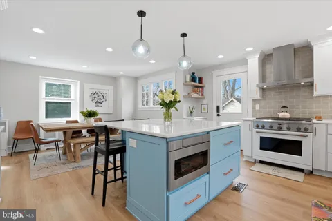 a kitchen with stainless steel appliances kitchen island granite countertop a stove a sink a dining table and chairs with wooden floor