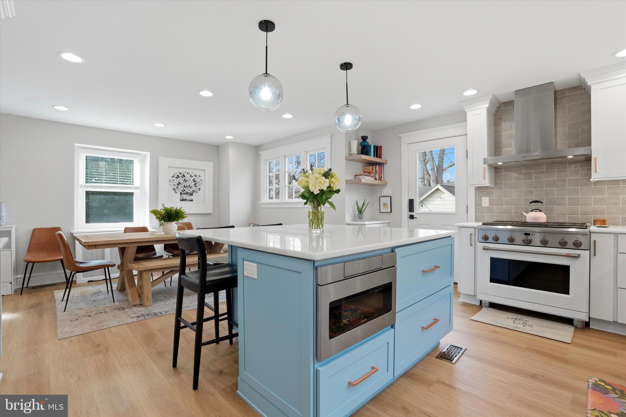 310 Old Forest Road Wynnewood, PA 19096 - Photo 21 of 35 a kitchen with stainless steel appliances kitchen island granite countertop a stove a sink a dining table and chairs with wooden floor