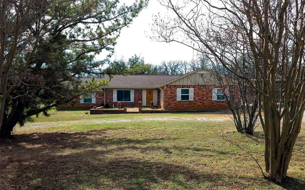 285 Montgomery Road Mineral Wells, TX 76067 - Photo 2 of 26 a front view of a house with a garden and trees