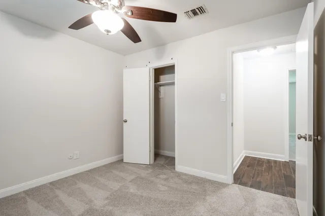 an empty room with closet and a chandelier fan
