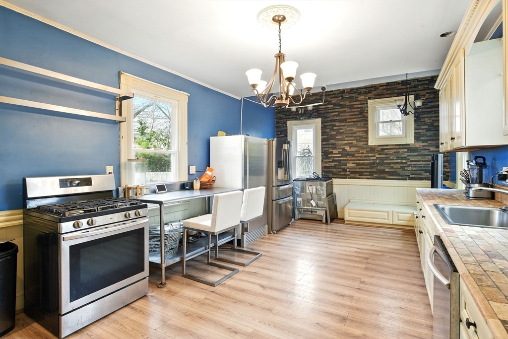 346 Maple Street Springfield, MA 01105 - Photo 14 of 36 a kitchen with stainless steel appliances granite countertop a stove top oven a sink dishwasher a dining table and chairs with wooden floor