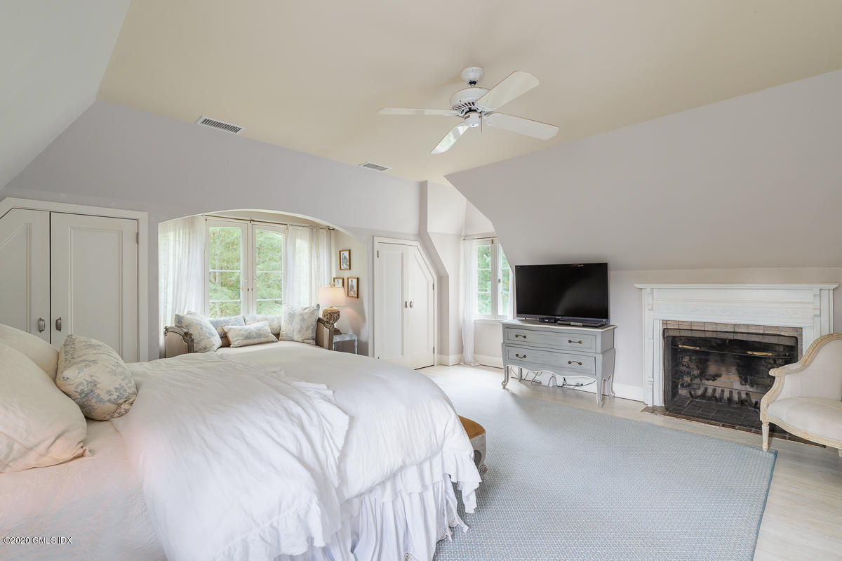 10 Frost Road Greenwich, CT 06830 - Photo 15 of 24 a bedroom with a bed a flat screen tv and a fireplace