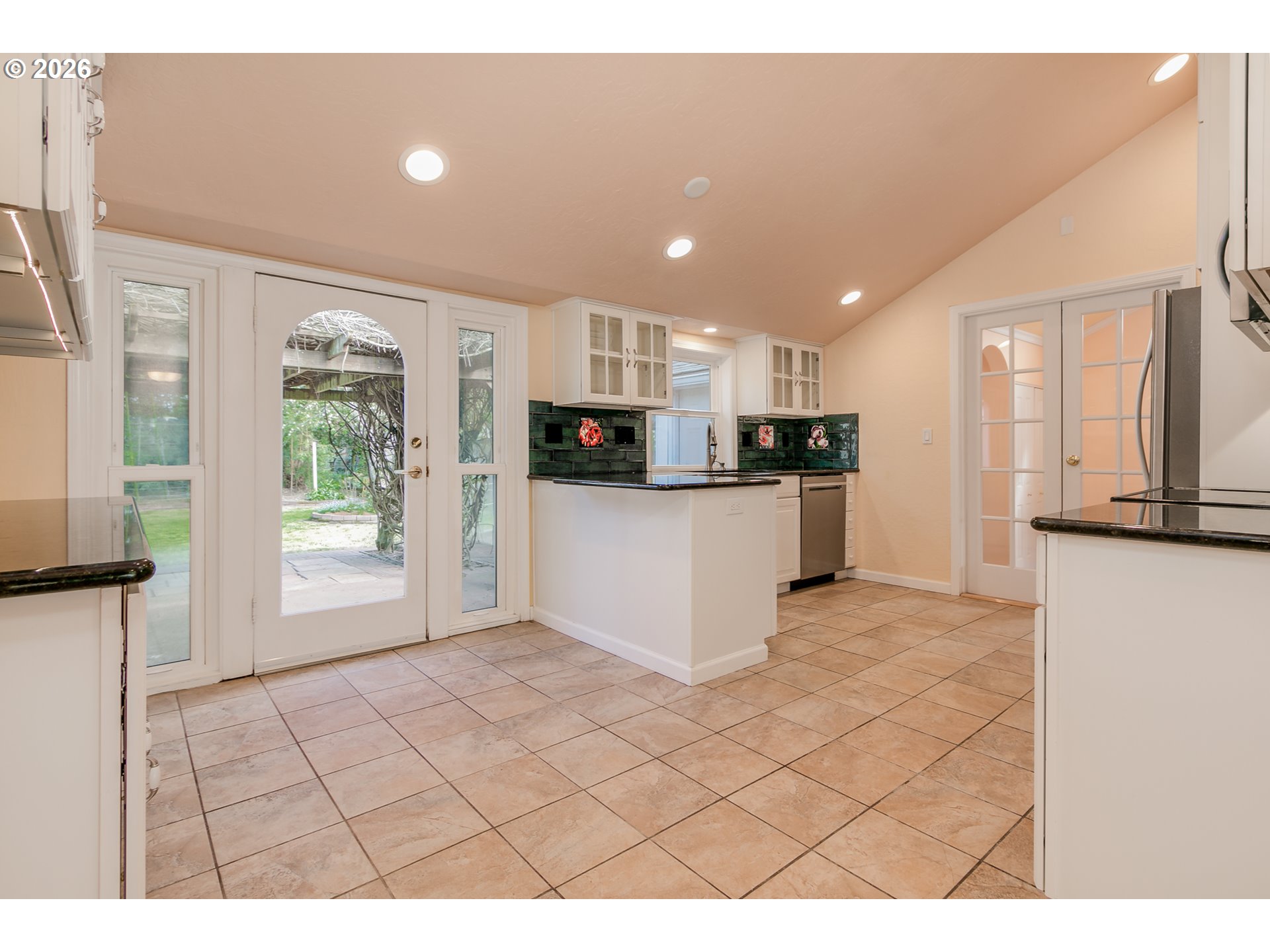 715 Ellsworth Street Eugene, OR 97402 - Photo 6 of 26 a kitchen with stainless steel appliances kitchen island granite countertop a refrigerator a stove a sink dishwasher and white cabinets with wooden floor