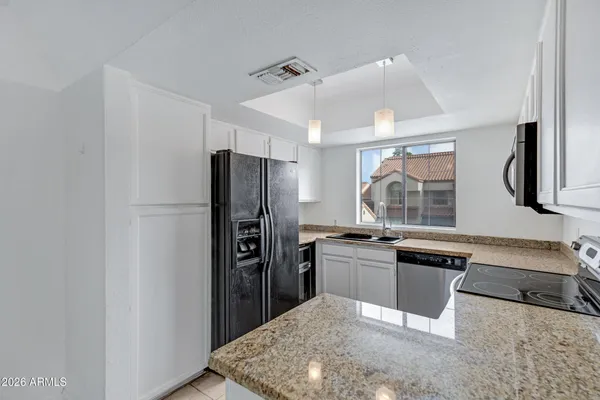 a kitchen with stainless steel appliances granite countertop a sink a stove and a microwave oven with cabinets