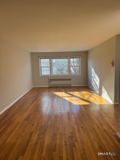 236 Glenbrook Road, Unit 12A Stamford, CT 06906 - Photo 18 of 18 an empty room with wooden floor and windows