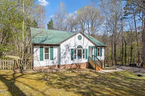 a view of a house with a yard and large trees
