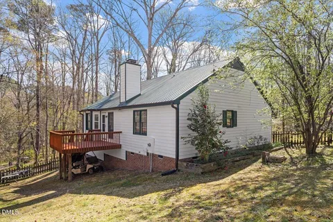 a view of a house with a yard chairs and wooden fence