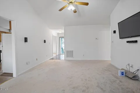 a view of an empty room with a ceiling fan and window