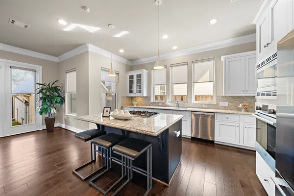 a kitchen with sink stove and white cabinets with wooden floor