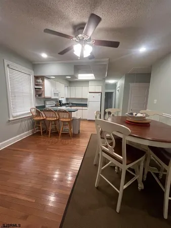 a dining room with wooden floor a chandelier a glass table and chairs