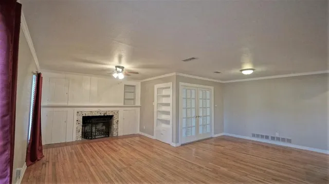 an empty room with windows fireplace and wooden floor