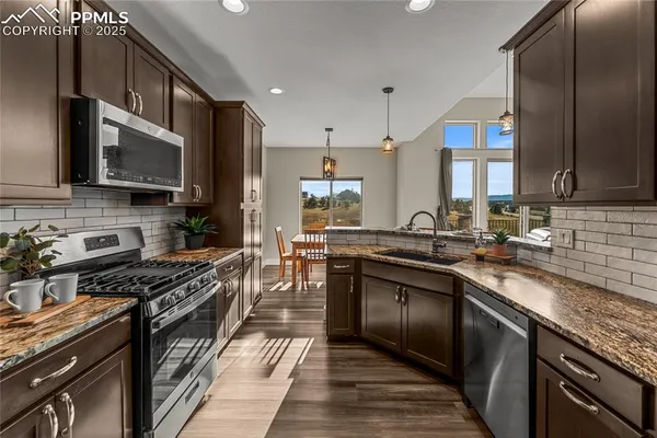 a kitchen with stainless steel appliances a sink dishwasher a stove top oven a refrigerator and cabinets