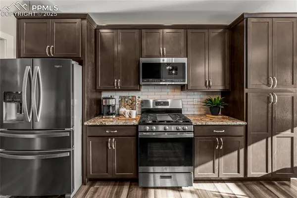 a kitchen with granite countertop a refrigerator stove and microwave