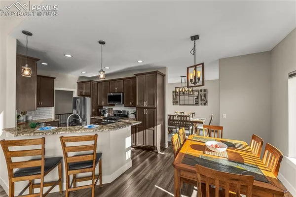 a kitchen with a stove a refrigerator and a dining table with wooden floor
