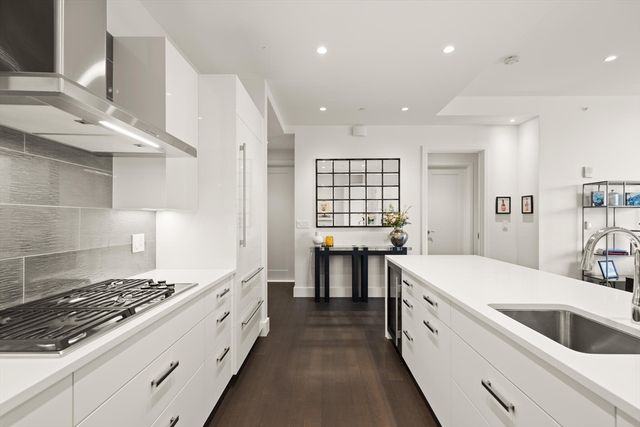 a large white kitchen with stainless steel appliances granite countertop a stove and a sink