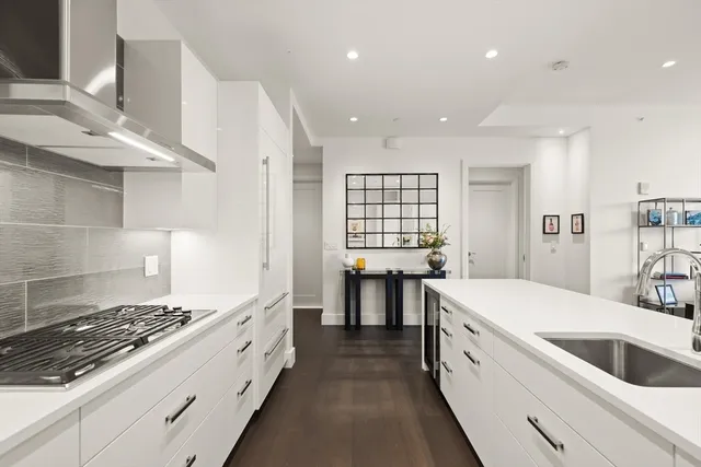 a large white kitchen with stainless steel appliances granite countertop a stove and a sink