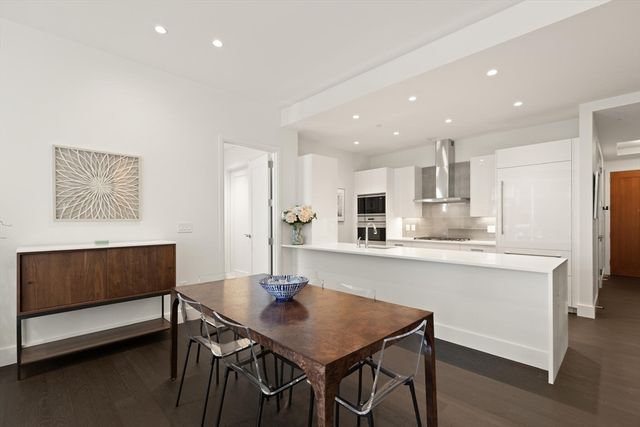 a kitchen with stainless steel appliances kitchen island granite countertop a dining table chairs and a refrigerator