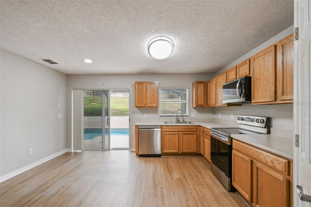 1854 Ridge Valley Street Clermont, FL 34711 - Photo 20 of 73 a large kitchen with stainless steel appliances granite countertop wooden cabinets a sink a stove and a wooden floors