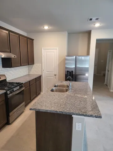 a kitchen with kitchen island granite countertop a sink stove and refrigerator