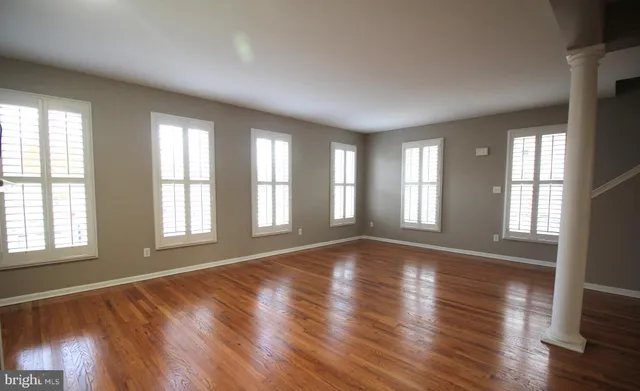 an empty room with wooden floor and windows