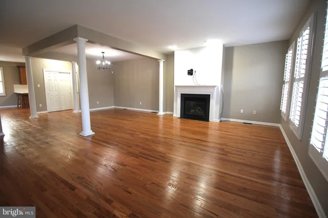 a view of an empty room with wooden floor fireplace and a window