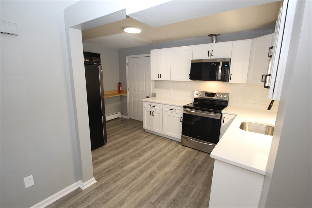 299 Main Street, Unit 2 North Reading, MA 01864 - Photo 15 of 35 a kitchen with cabinets and wooden floor