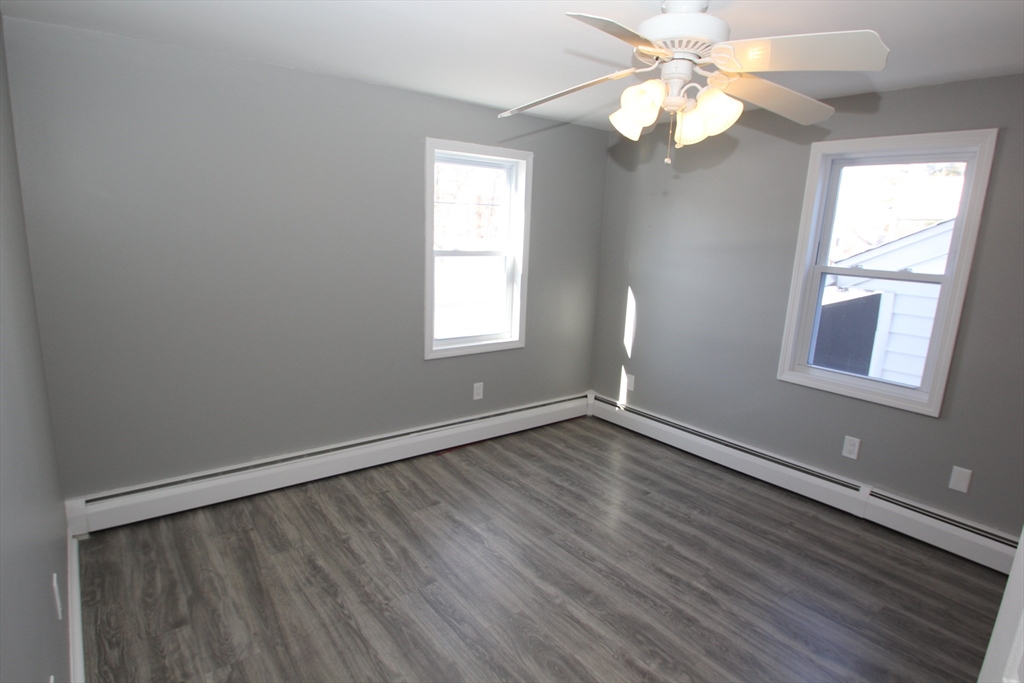 299 Main Street, Unit 2 North Reading, MA 01864 - Photo 29 of 35 an empty room with wooden floor fan and windows