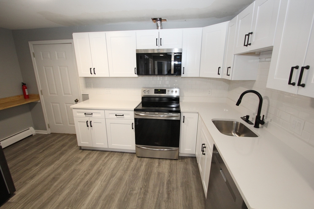 299 Main Street, Unit 2 North Reading, MA 01864 - Photo 8 of 35 a kitchen with a sink a stove and cabinets