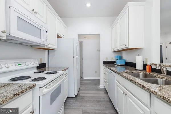 a kitchen with granite countertop cabinets and white appliances