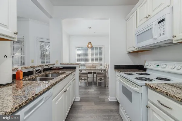 a kitchen with stainless steel appliances granite countertop a stove a sink and a granite counter tops with white cabinets