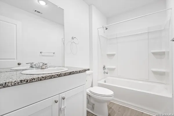 a bathroom with a granite countertop sink toilet a mirror and bathtub