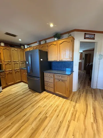 a kitchen with stainless steel appliances wooden floor and wooden cabinets