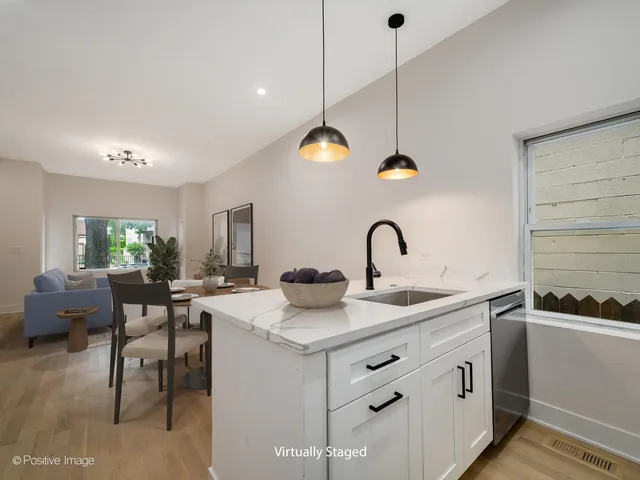 a kitchen with stainless steel appliances kitchen island a stove a sink a dining table and chairs with wooden floor