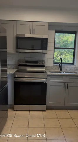 a kitchen with granite countertop a stove top oven cabinetry a sink and a window