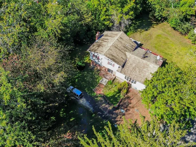 an aerial view of a house with a yard and trees all around