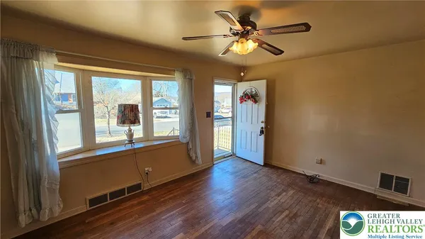 a view of an empty room with a window and wooden floor