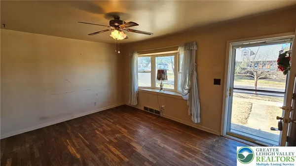a view of an empty room with a window and wooden floor