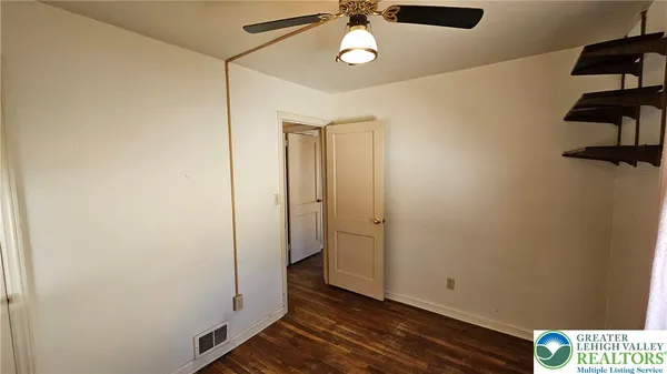 an empty room with wooden floor closet and windows