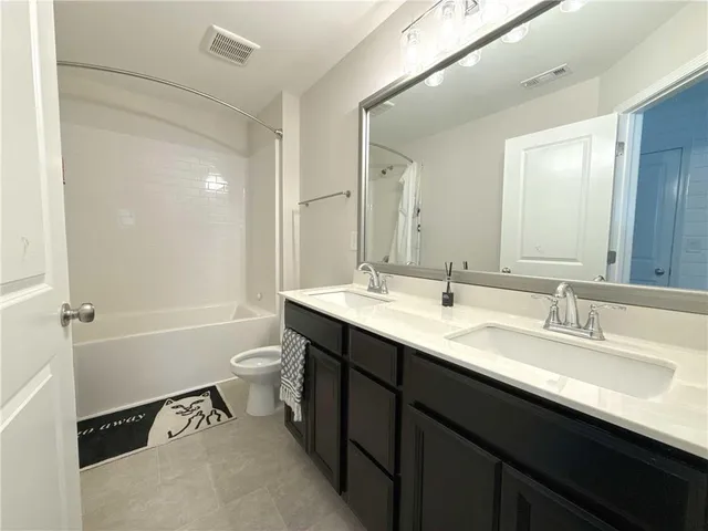 a bathroom with a double vanity sink toilet mirror and bathtub