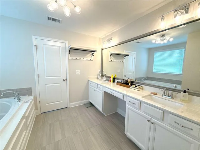 a large white bathroom with a granite countertop sink mirror and a bathtub