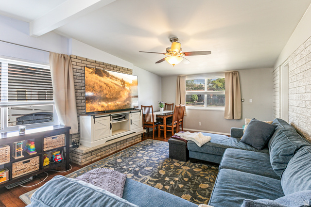 1619 Davis Drive Layton, UT 84041 - Photo 19 of 27 Family area featuring wood like flooring, exposed ceiling beams, and a exposed brick wall with a large wood burning fireplace.