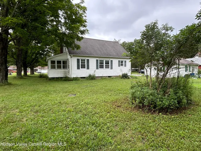 a view of a house with a big yard and large trees