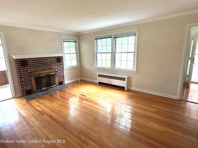 an empty room with wooden floor fireplace and windows