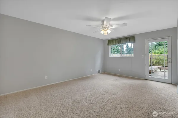 an empty room with windows and fan