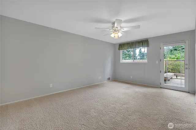an empty room with windows and fan