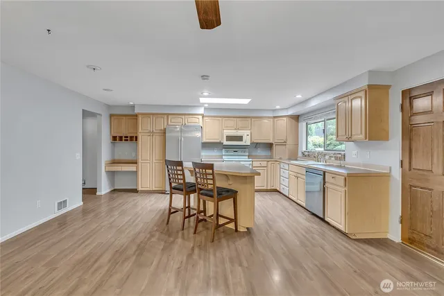 a kitchen with white cabinets wooden floor table and chairs