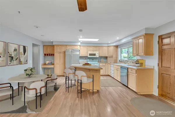 a kitchen with stainless steel appliances granite countertop a stove top oven a sink dishwasher a dining table and chairs with wooden floor