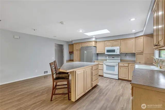 a kitchen with a table chairs wooden floors and white stainless steel appliances