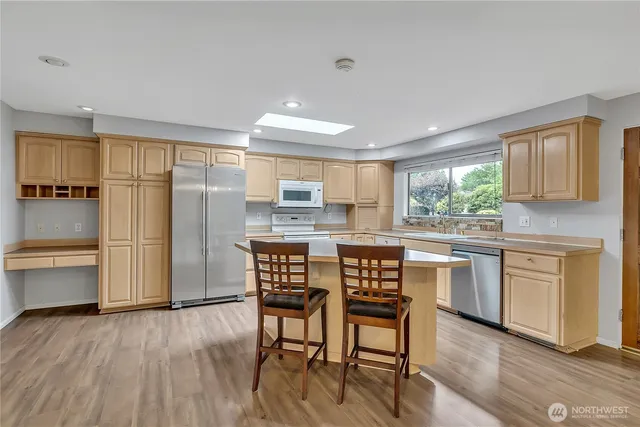 a kitchen with stainless steel appliances granite countertop a stove top oven a sink dishwasher a dining table and chairs with wooden floor